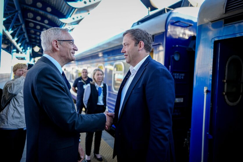 Zwei Männer (Lars Klingbeil und Martin Jäger) schütteln einander an einem Bahnhof die Hände