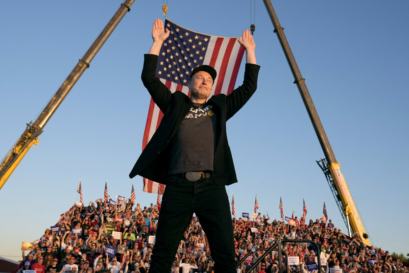 Ein Mann, Elon Musk, hält die US-Flagge über seinem Kopf