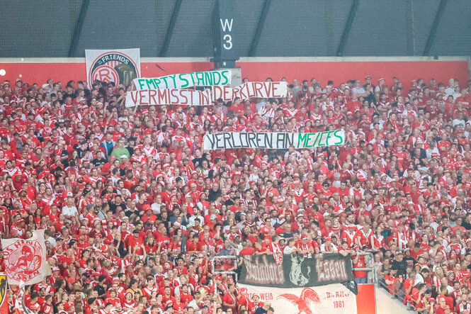 Eine Fankurve mit Bannern, darauf steht: "Empty Stands. Vermisst in der Kurve. Verloren an ME/CFS"