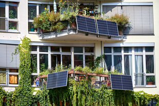 Ein begrüntes Haus mit Balkonen, an denen Photovoltaikanlagen befestigt sind