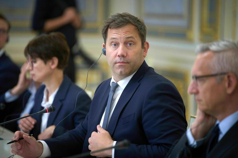 Karsten Klingbeil sitzt mit Headphones an einem Tisch mit seiner Delegation und schaut in die Kamera