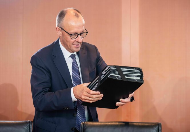 Friedrich Merz legt eine Aktentasche auf den Kabinettstisch