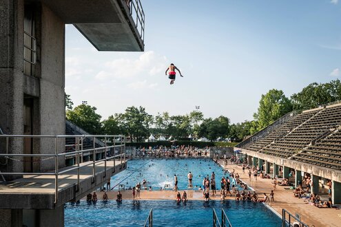Olympiabad, ein Mensch springt gerade vom Sprungturm