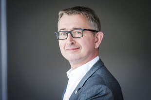 Dr. Joachim Rock, ein Mann mittlerenen Alters mit Brille, leicht lächelnd