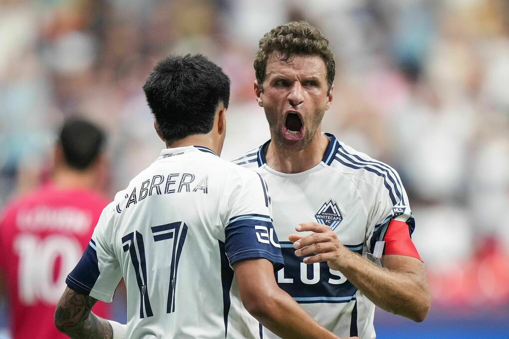 Thomas Müller mit weit aufgerissenem Mund wird von einem Mitspieler beglückwünscht