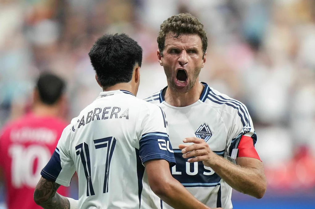 Thomas Müller mit weit aufgerissenem Mund wird von einem Mitspieler beglückwünscht
