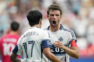 Thomas Müller mit weit aufgerissenem Mund wird von einem Mitspieler beglückwünscht