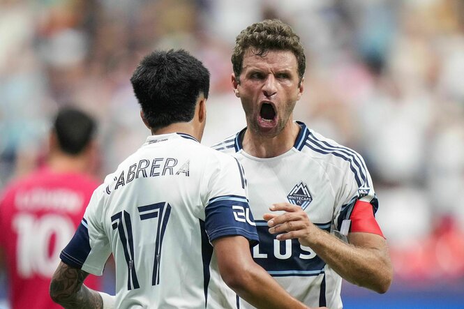 Thomas Müller mit weit aufgerissenem Mund wird von einem Mitspieler beglückwünscht