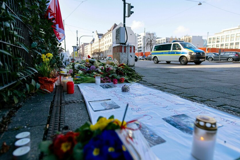 Ein Einsatzfahrzeug der Polizei fährt an Blumen und Kerzen nahe der Stelle in der Innenstadt vorbei, wo am 13.02.2025 ein Auto in eine Gruppe von Demonstranten gefahren war