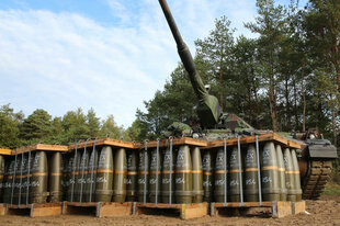 Paletten voller Munition stehen vor einer Panzerhaubitze