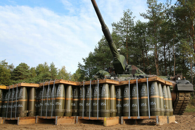 Paletten voller Munition stehen vor einer Panzerhaubitze