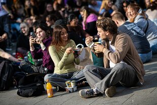 Personen sitzen zusammen auf dem Boden und essen Pudding