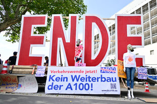 Demonstranten gegen den Weiterbau der A100 stehen vor Beginn eines Bildtermins zur offiziellen Freigabe an der Auf- und Ausfahrt Am Treptower Park der A100