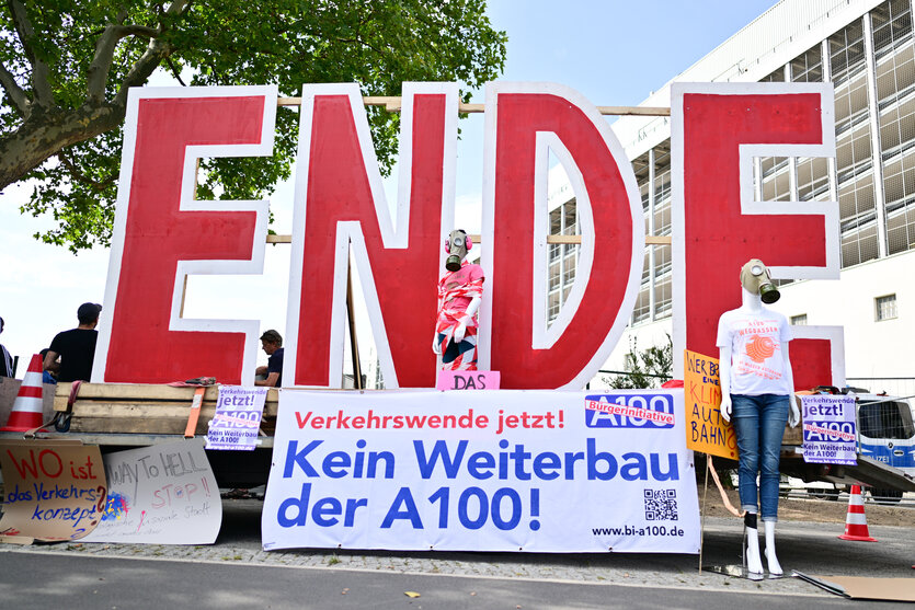 Demonstranten gegen den Weiterbau der A100 stehen vor Beginn eines Bildtermins zur offiziellen Freigabe an der Auf- und Ausfahrt Am Treptower Park der A100