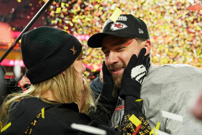 Taylor Swift hält den Kopf ihre nun Verlobten Travis Kelce in den Händen, sie werden umflattert vonPapierschnipseln nach einem Football-Sieg von ihm