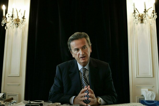 Riad Salameh vor einem hoch-herrschaftlichem Hintergrund, die Hände aufeinander wie Mr Burns und in Anzug und Krawatte