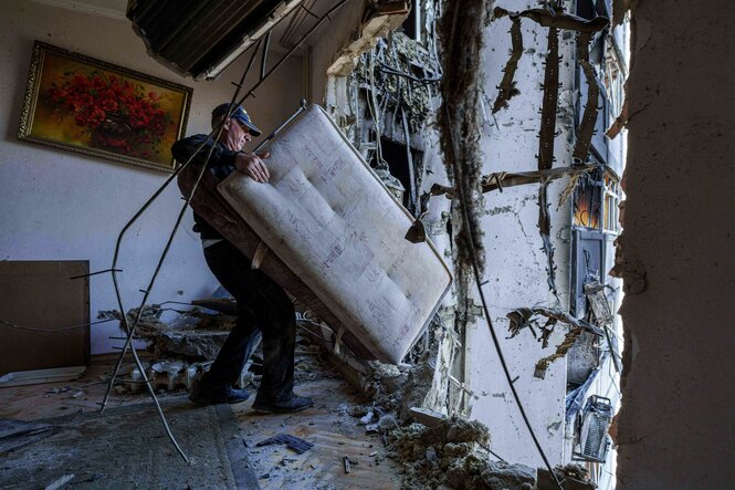 Ein Mann trägt ein Sofa aus seiner zerstörten Wohnung