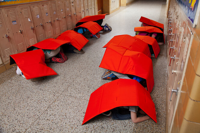 Kinder verstecken sich im Schulgang unter schusssicheren Decken