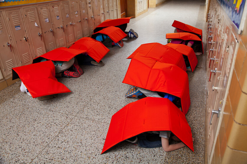 Kinder verstecken sich im Schulgang unter schusssicheren Decken