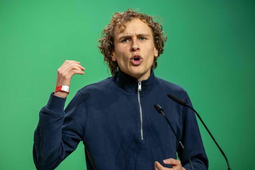 Jakob Blasel vor einer Partei Grünen Wand, hart am argumentieren