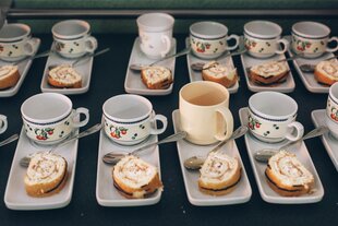 Mehrere identische Teller mit Kuchenstücken und Tassen