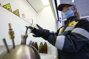 Die Mitarbeiterin der Nowokuibyschewsk-Raffinerie, einer Tochtergesellschaft der Rosneft Oil, schüttet eine braun-schwarze Flüssigkeit in einen Metallbehälter