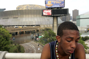 Ein junger Mann weint, im Hintergrund das Football-Stadion von New Orleans