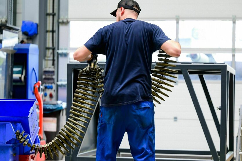 Ein Arbeiter steht an einem Pult und begutachtet Exerziermunition