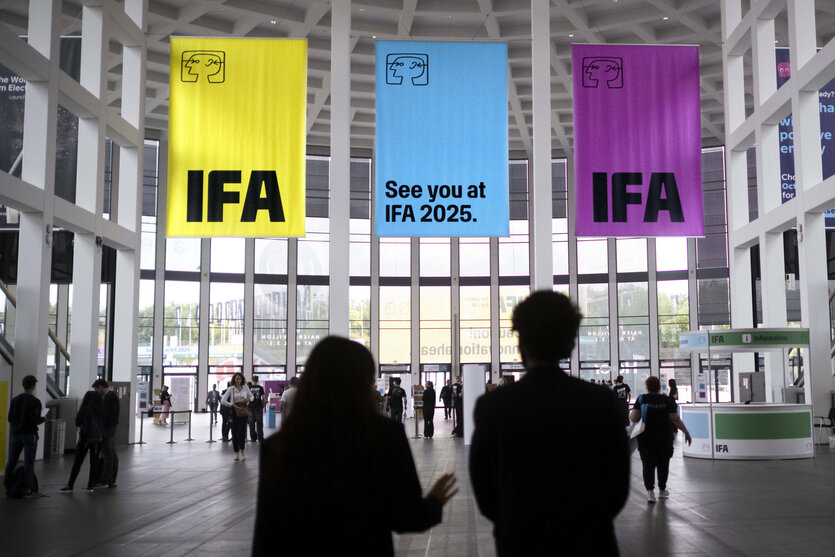 Menschen stehen in der Berliner Messer und schauen auf Banner der IFA