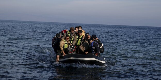 Menschen sitzen zusammengepfercht in einem Schlauchboot, das sich auf dem Wasser befindet.