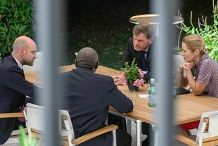EU-Außenpolitiker*innen an einem Tisch, diskutierend, durch Stäbe gesehen
