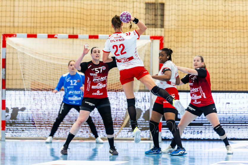 Handballspiel, eine Frau springt hoch und will den Ball ins Tor werfen, eine Frau steht vor ihr und will blocken