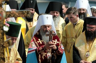 Onufrij (M), Metropolit hält in vollem Ornat ein Kreuz in der Hand, er ist umringt von Geistlichen