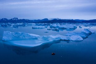 Ein Boot navigiert große Eisberge in der Nähe von Kulusuk, im östlichen Grönland