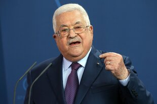 Mahmud Abbas vor blauem Hintergrund. Er macht eine Geste mit seiner linken Hand