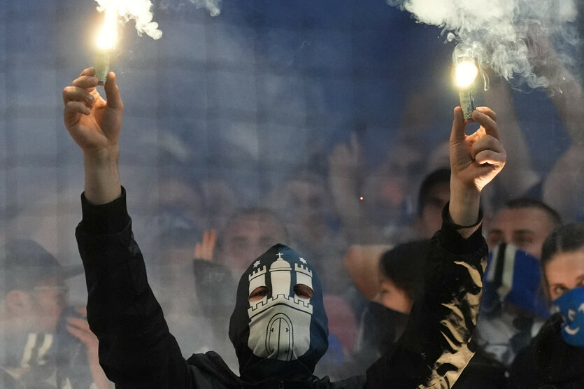 HSV-Fan steht auf der Tribüne im Volksparkstadion und hält zwei Pyros in die Luft
