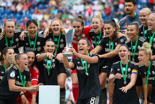 Lena Oberdorf hebt Pokal hoch, im Hintergrund das Team