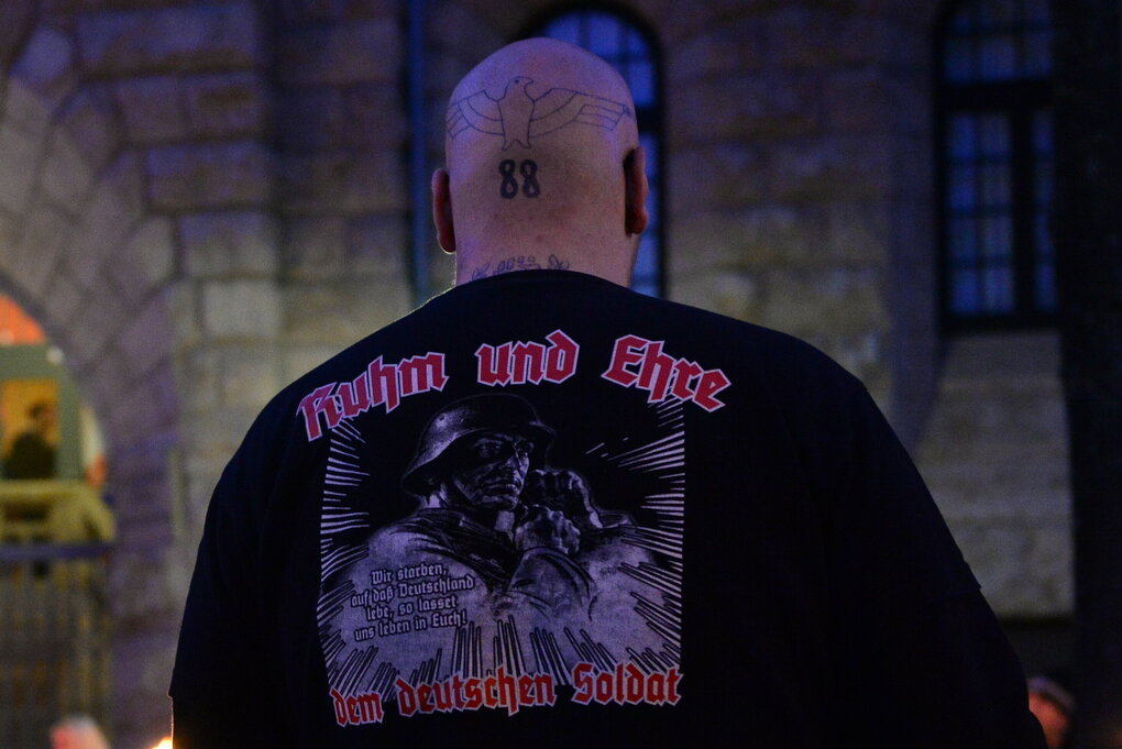 Ein Mann mit Glatze und "88"-Tatoo trägt ein T-Shirt mit der Aufschrift "Ruhm und Ehre dem deutschen Soldat".