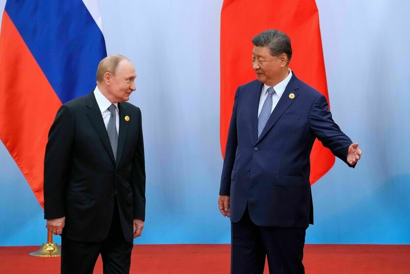 Zwei Männer (Wladimir Putin und Xi Jinping) stehen nebeneinander, einer von ihnen (Xi Jinping) macht eine einladenen Geste