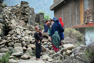 Eine afghanische Familie geht an einem zerstörten Haus vorbei