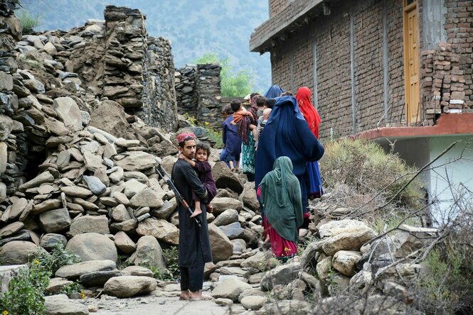 Eine afghanische Familie geht an einem zerstörten Haus vorbei