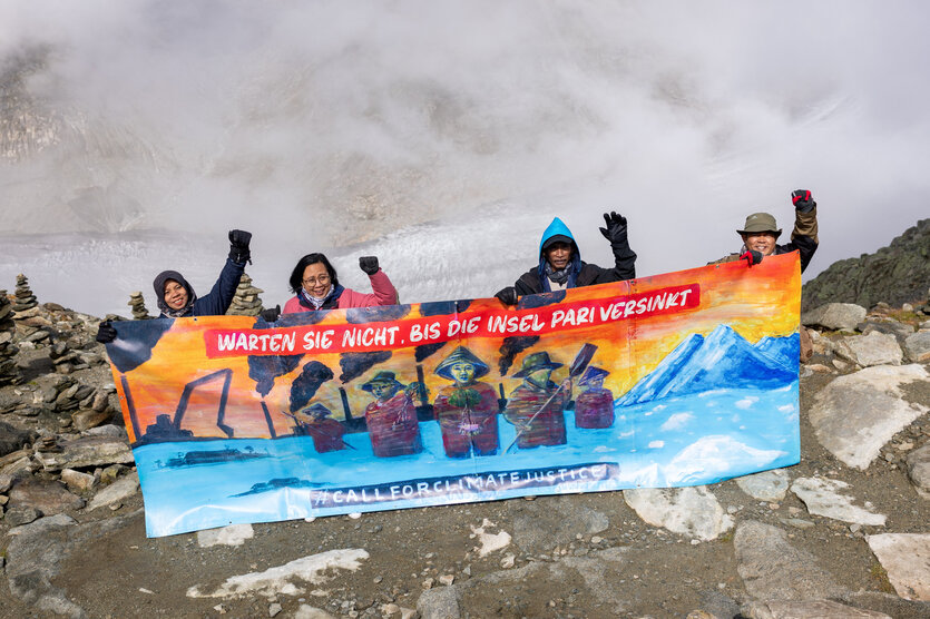 Protestierende halten ein Banner hoch, auf dem steht: „Wartet nicht, bis die Insel Pari versinkt.”