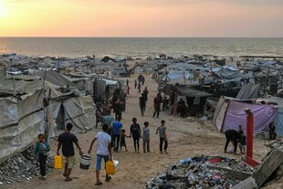 Vertriebene Palästinenser gehen durch ein behelfsmäßiges Lager am Strand von Gaza-Stadt
