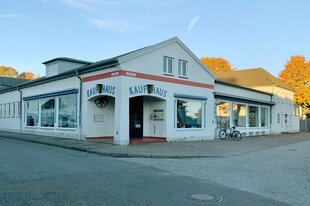 Ein Gebäude mit der Aufschrift "Kaufhaus" und "Museum", umgeben von Herbstbäumen, mit einem Fahrrad davor