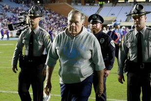 Belichick und drei Sicherheitskräfte im Hintergrund auf dem Rasen