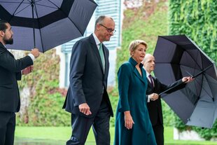 Eine Frau und ein Mann werden mit regenschirmen geschützt