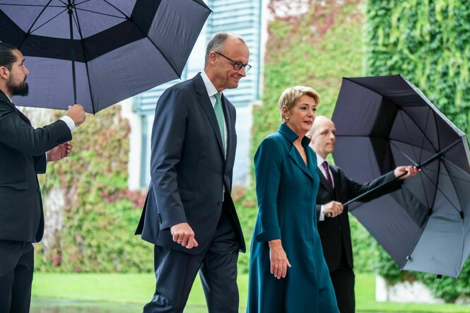 Eine Frau und ein Mann werden mit regenschirmen geschützt