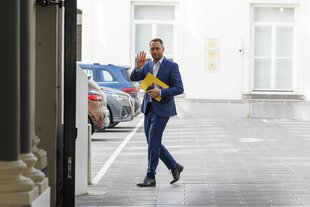 Maxime Prévot läuft über einen Parkplatz und winkt in die Kamera