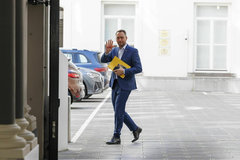 Maxime Prévot läuft über einen Parkplatz und winkt in die Kamera