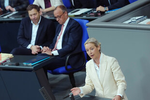Alice Weidel spricht in der Generaldebatte zum Haushalt im Plenum des Bundestags. Lars Klingbeil und Friedrich Merz sitzen hinter ihr und hören zu.